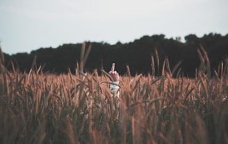 man hiding behind cattail plant