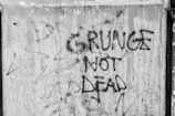 Close-up of a gritty punk band logo painted on a cracked wall.