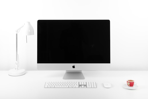 A sleek, minimalist workspace with a large monitor displaying real-time Bitcoin infrastructure data on a white background.