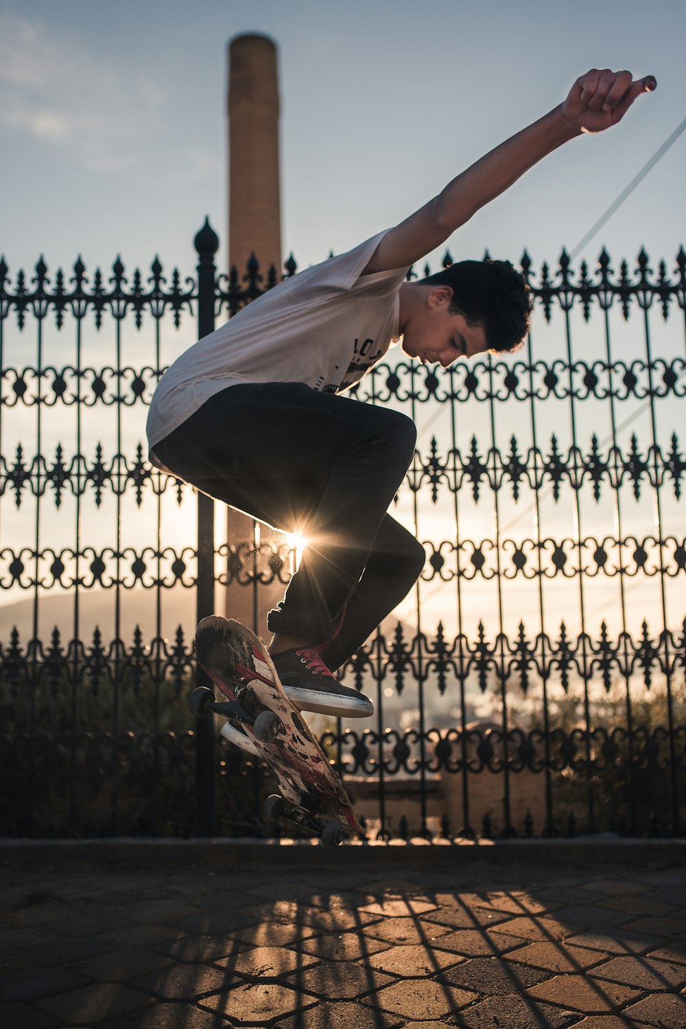 Mann macht tagsüber einen Skateboard-Trick in der Nähe eines schwarzen Stahlzauns