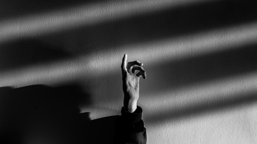 grayscale photography of person raising his hand