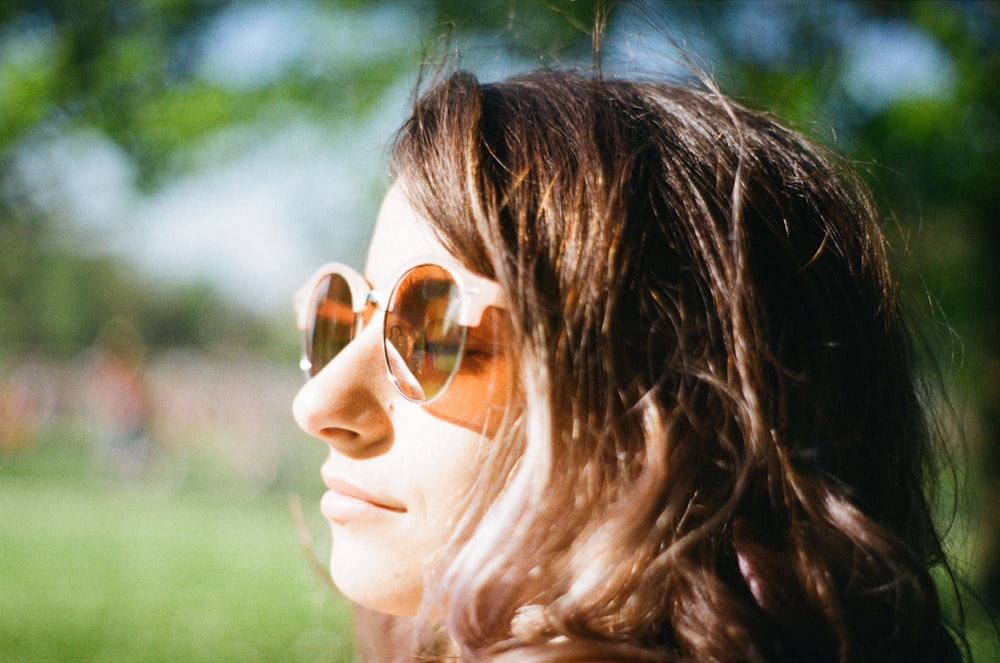 femme fermant les yeux portant des lunettes de soleil à verres bruns