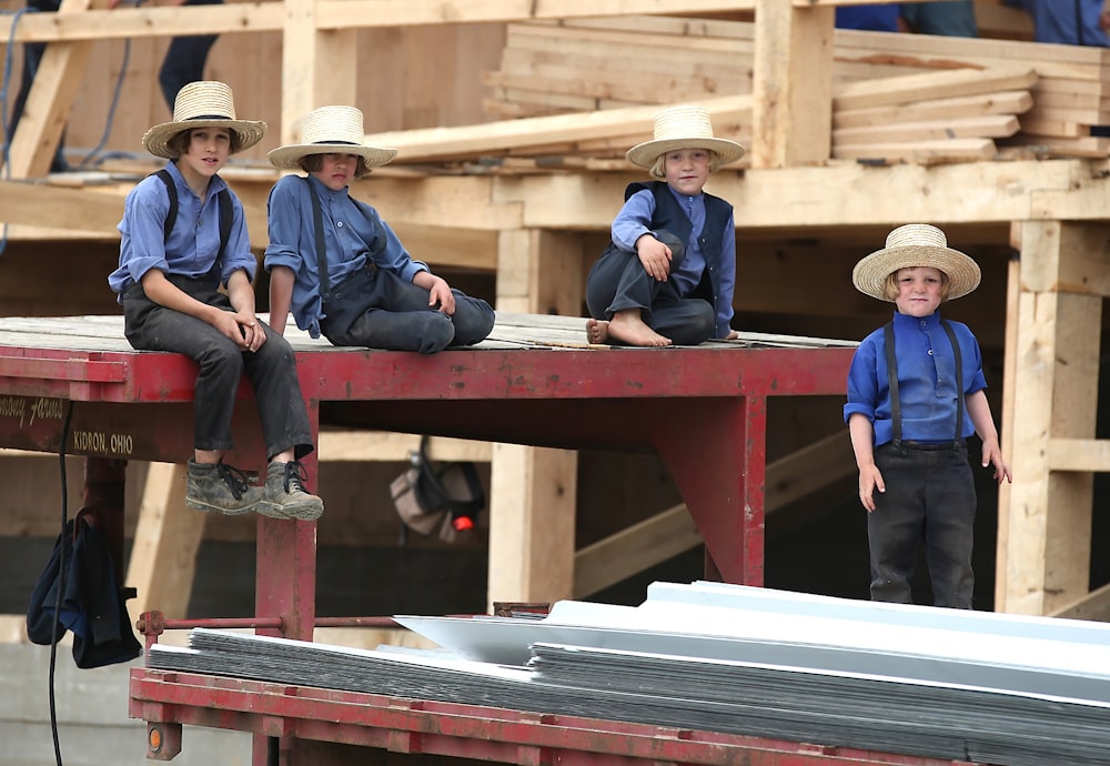 four boys sitting on red steel frame