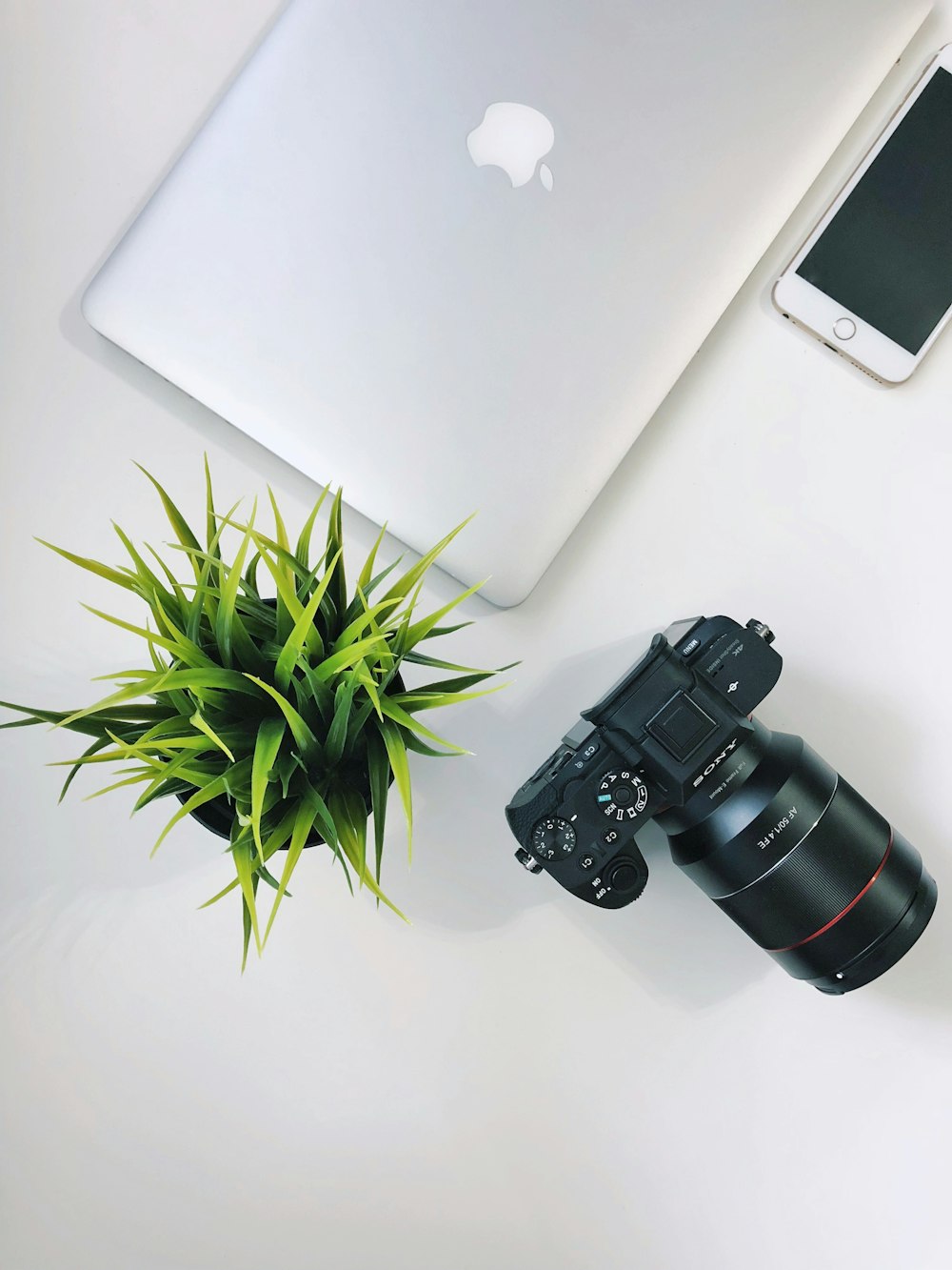 MacBook plateado cerca de la cámara DSLR Sony negra