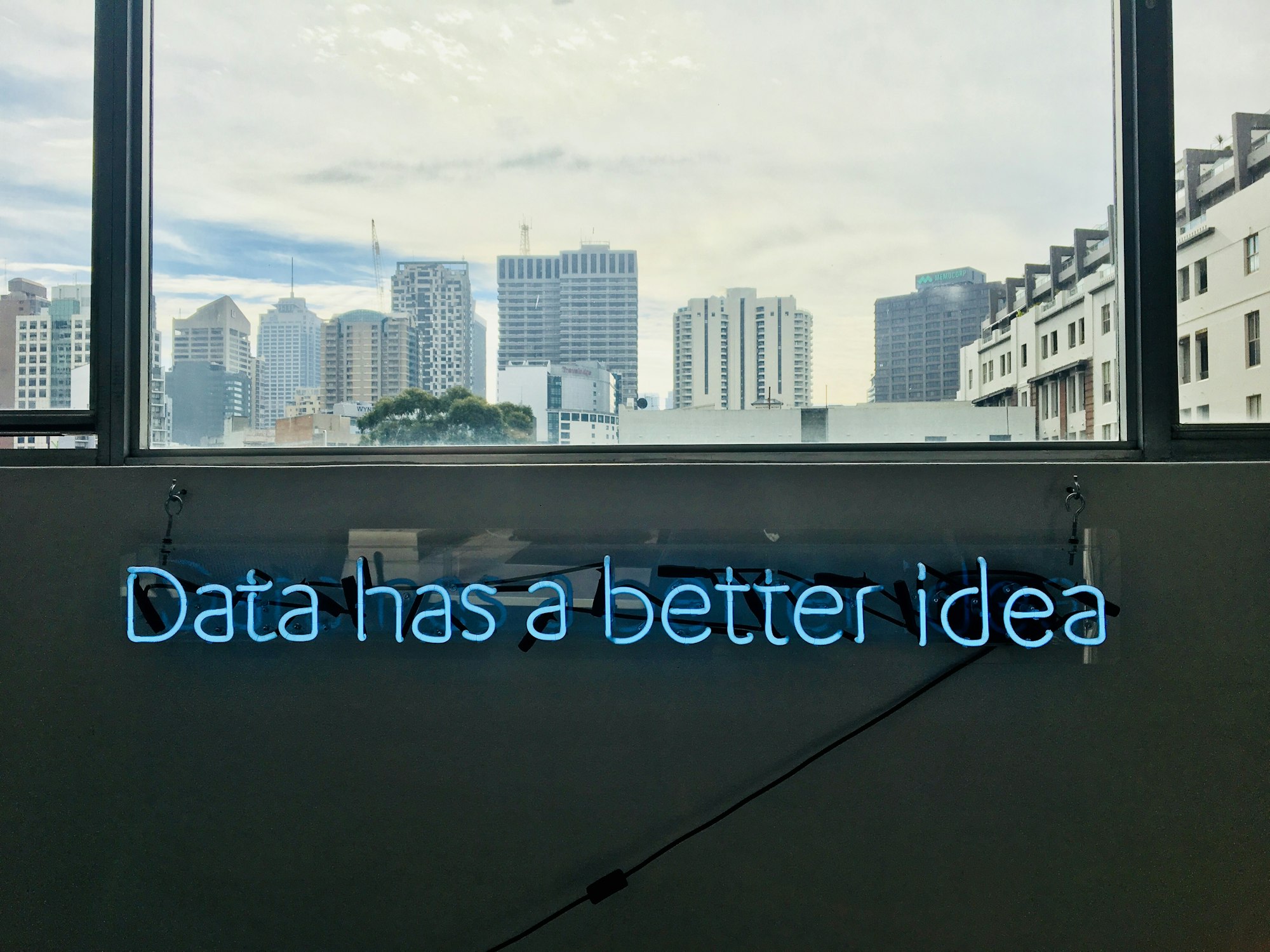 Neon sign in a building under a window that reads "Data has a better idea".