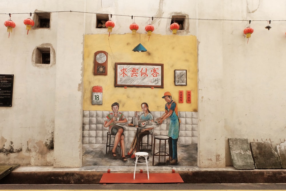 two women sitting while waiter is serving painting