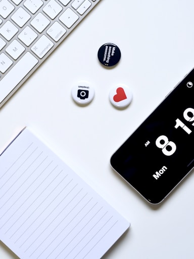a white desk with a keyboard, phone, and magnets