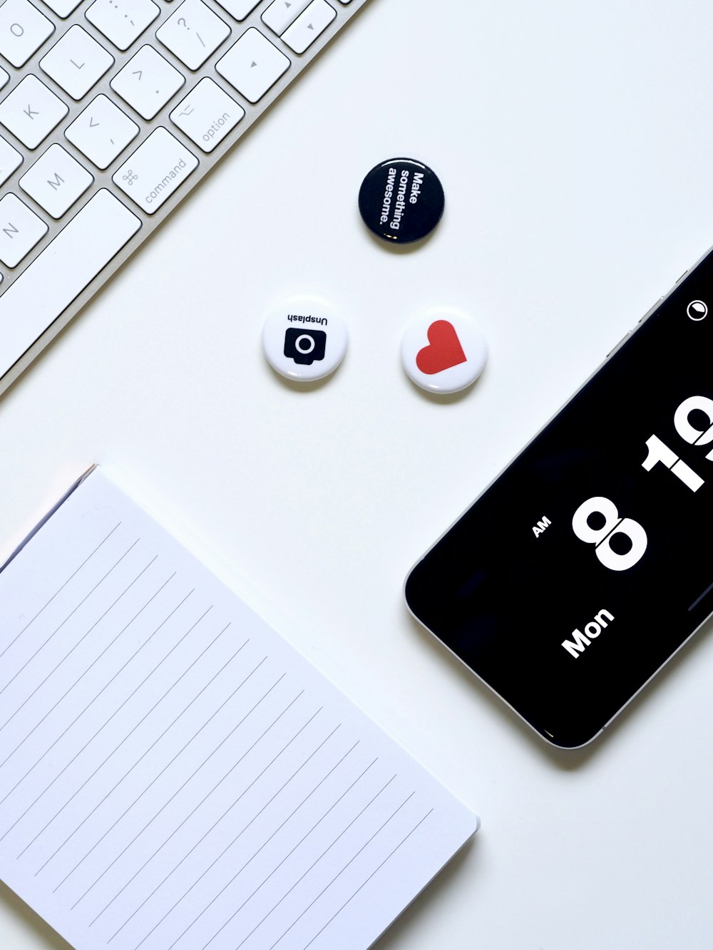 a white desk with a keyboard, phone, and magnets