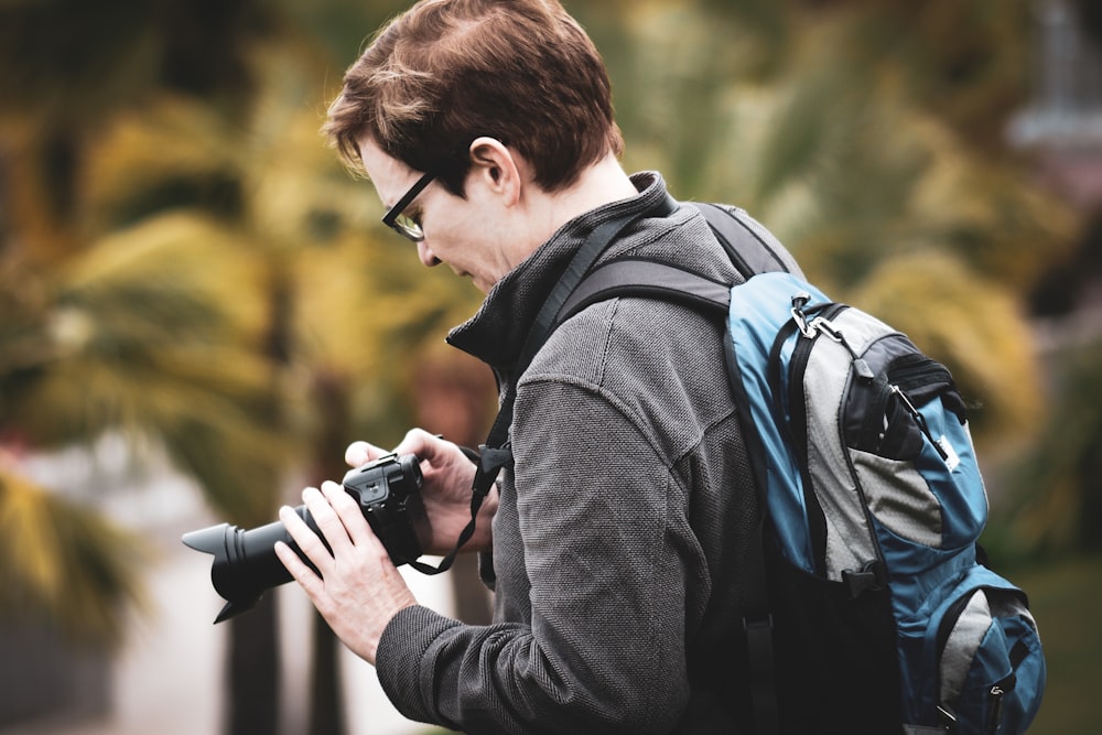 man holding black DSLR camera