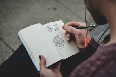 A close-up of a hand sketching intricate designs in a notebook.