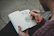 A close-up shot of hands sketching outdoors with nature in the background.