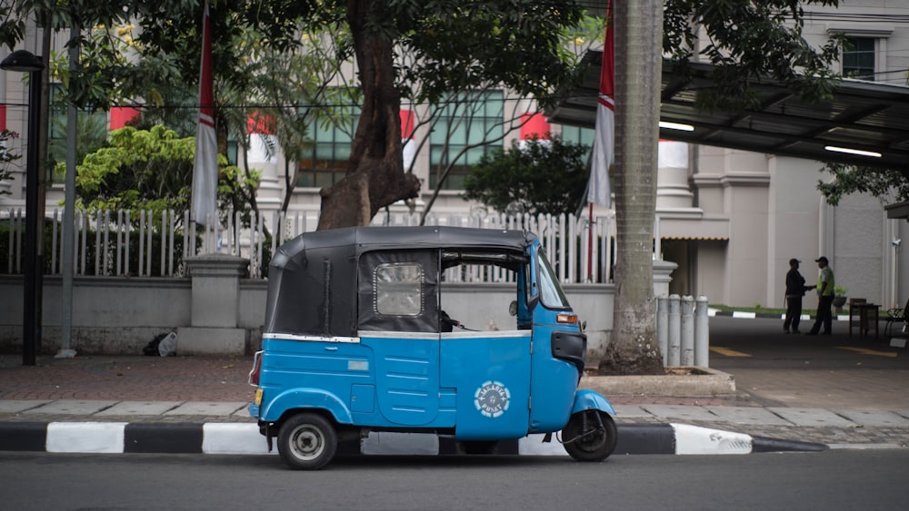 rickshaw automático negro y azul en carretera de concreto gris