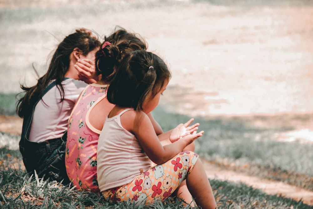 three children sitting on grass