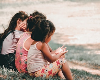 three children sitting on grass