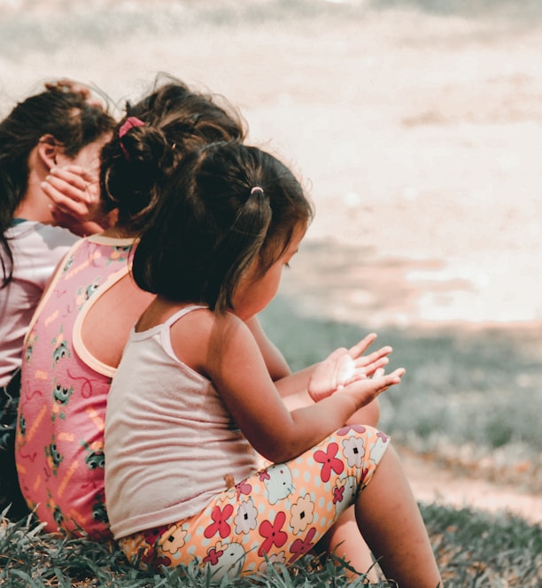 three children sitting on grass