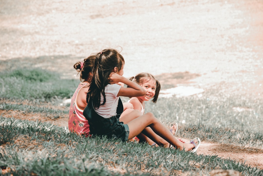 three children sitting on grass,