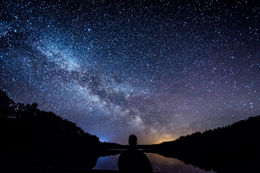 silhouette of person standing under starry sky