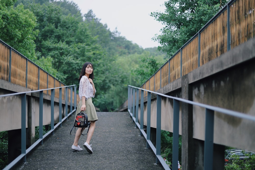 woman standing on walkway holding backpack