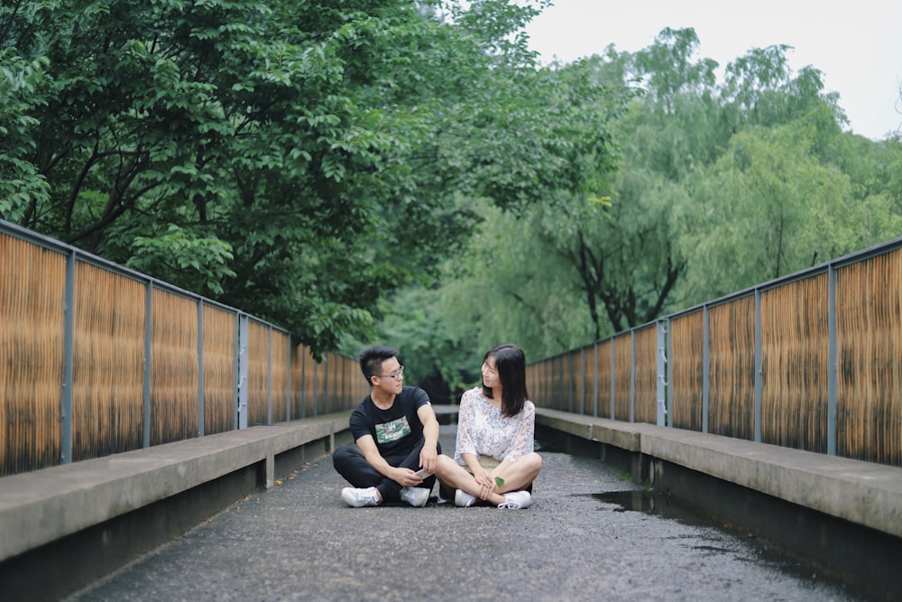 man and woman sitting on floor near trees