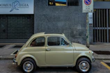 A clean and shiny Fiat 500 being serviced, with summer tires being switched by a friendly staff member.