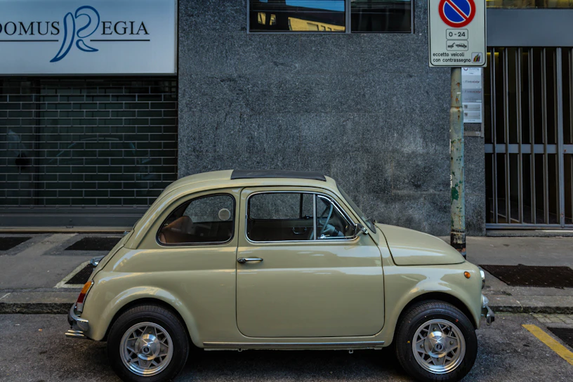 A shiny Fiat 500 parked in front of the Sternwerk autohaus on a sunny day.