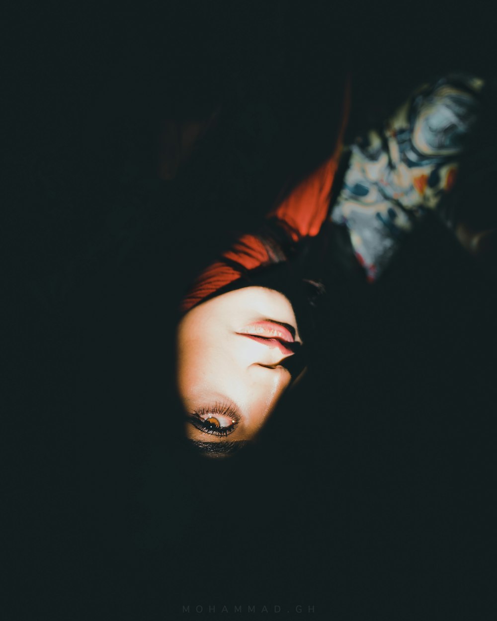 a woman laying down in the dark with her eyes closed