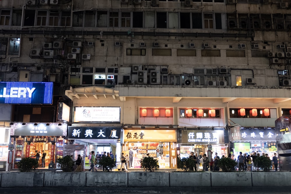 foule les gens près des bâtiments en béton blanc la nuit