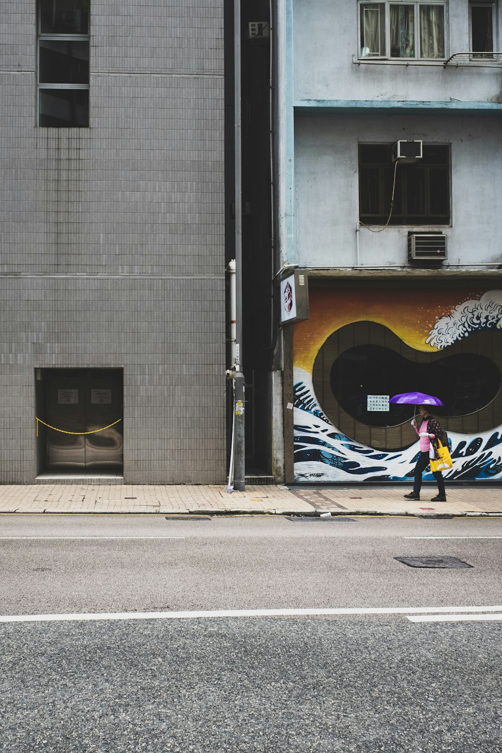 person holding up purple umbrella walking on sidewalk