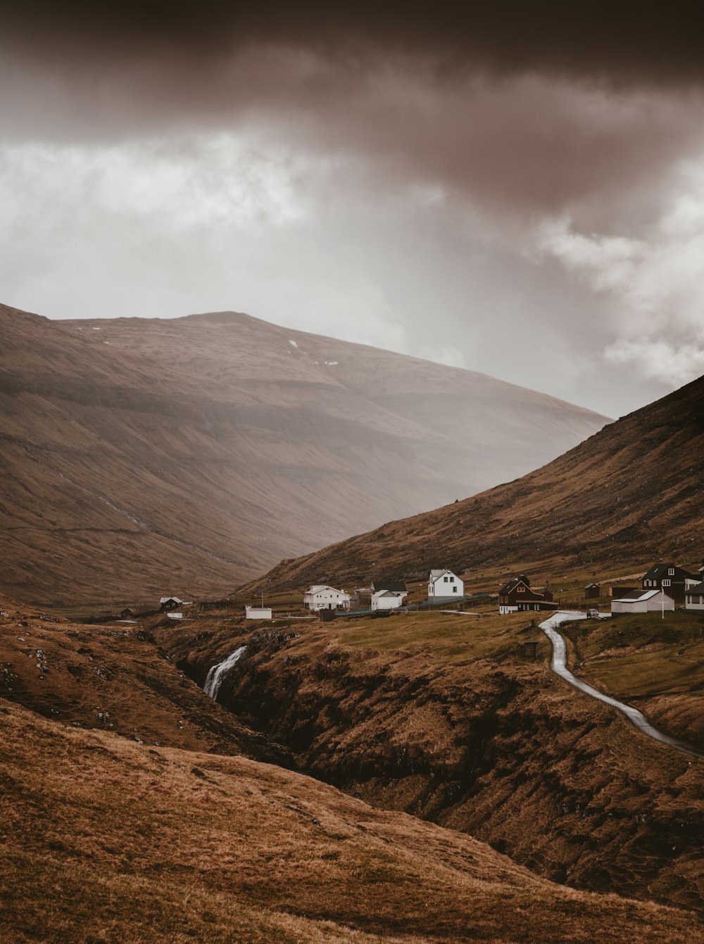 houses near mountain under cloudy sky