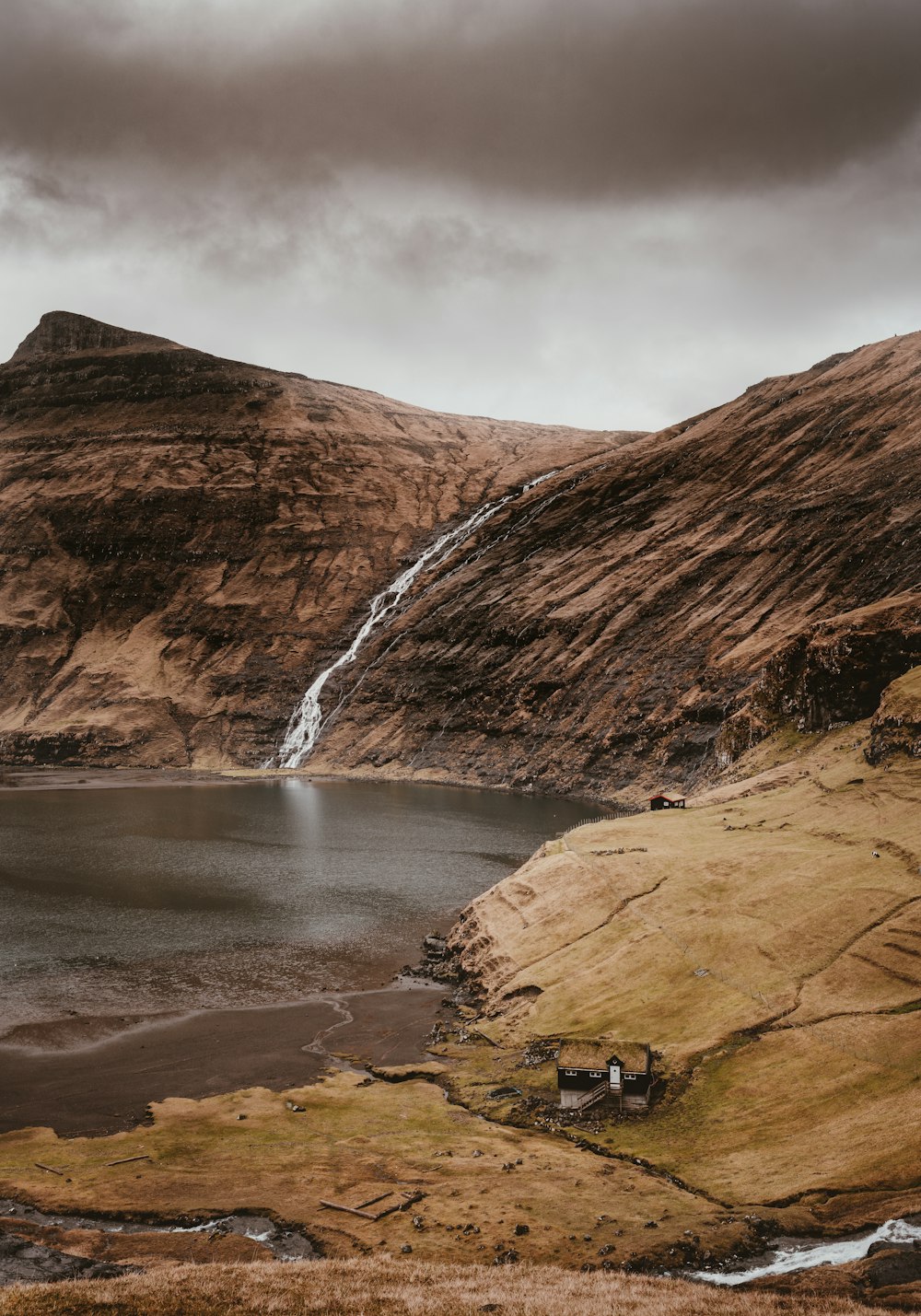 photo of brown mountains beside body of wate