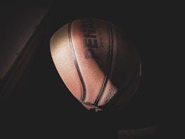 Close-up of a basketball spinning on a finger against a dark background.