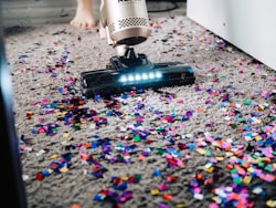 A cleaner in uniform carefully vacuuming an office carpet.