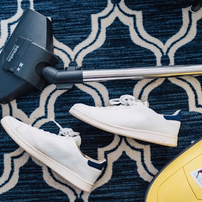 pair of white sneakers beside vacuum cleaner