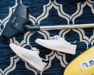 pair of white sneakers beside vacuum cleaner