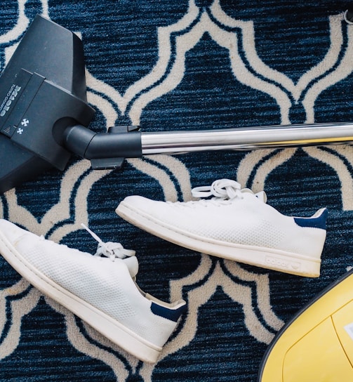 pair of white sneakers beside vacuum cleaner