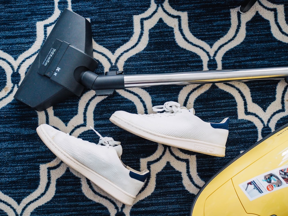 pair of white sneakers beside vacuum cleaner