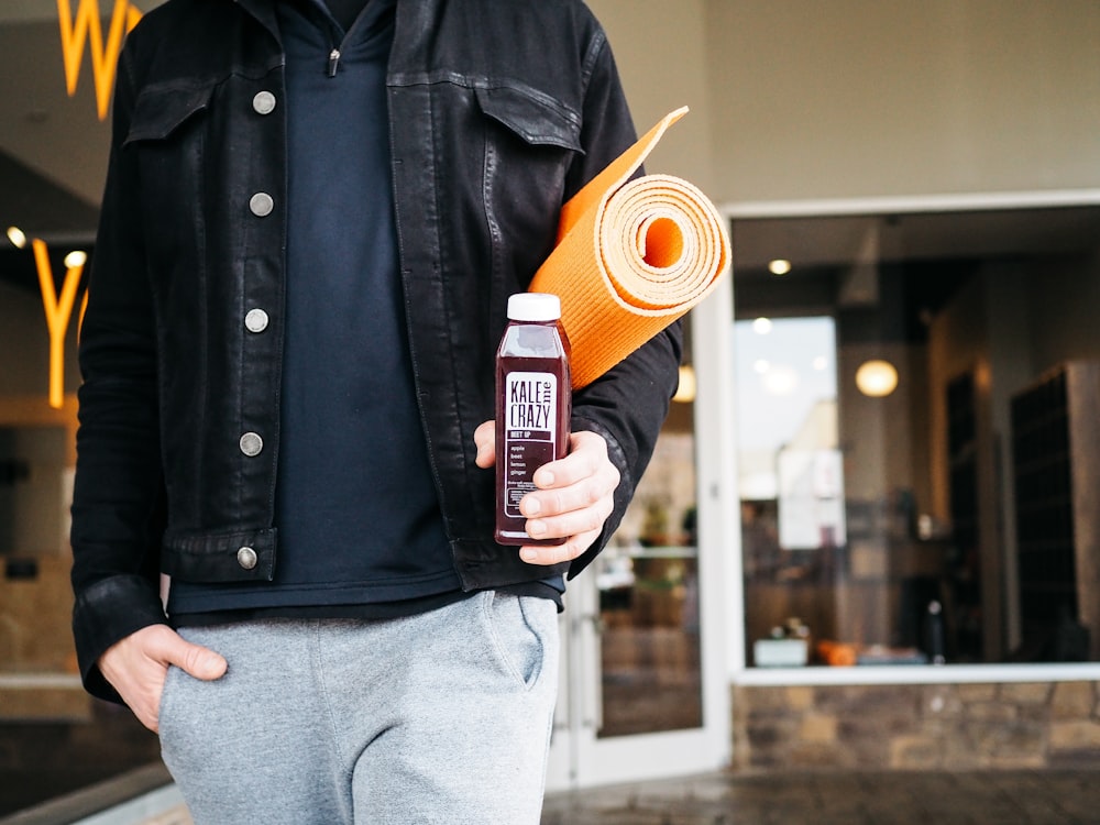 person holding plastic bottle filled with brown liquid