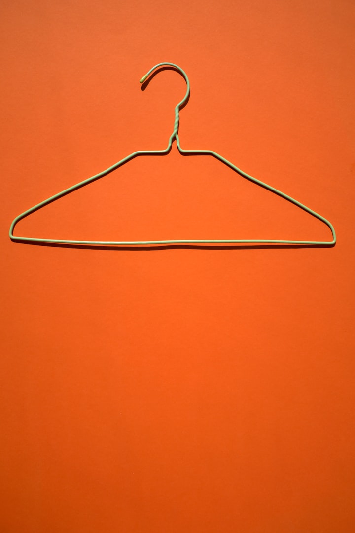 Leerer Kleiderhaken auf orangem Hintergrund