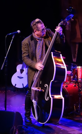 A musician passionately playing a double bass during a performance.