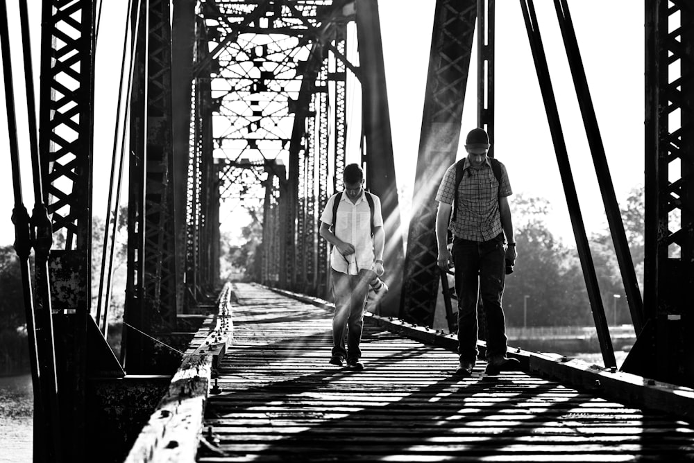 grayscale photography of two men on bridge