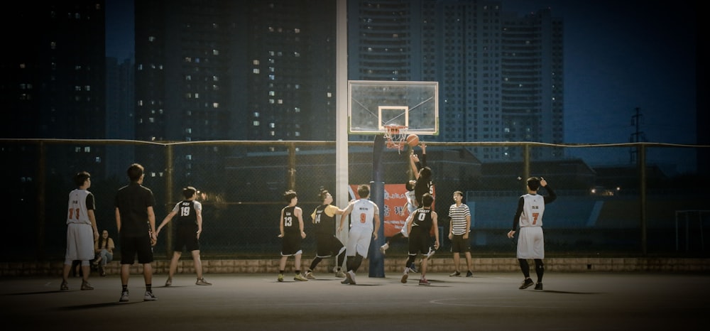 group of men playing basketball during nighttime