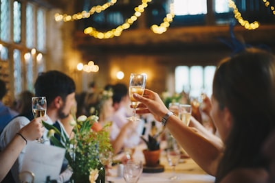 people raising wine glass in selective focus photography guest zoom background