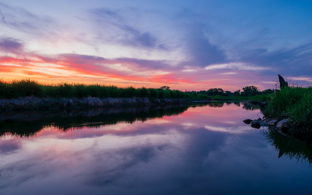 photo of body of water surrounded with grass field