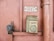 An old emergency phone mounted on a textured pink wall. It features a worn-out rectangular housing with an instruction label in French. Nearby, a metal pipe runs vertically alongside the wall.