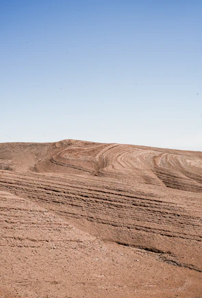 Golden desert dunes under a vast, clear blue sky.