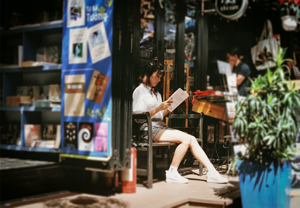 woman reading book sitting on bench