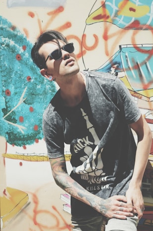 A close-up shot of a model wearing a bold, graphic tee from dawid mattya llc, standing against an urban graffiti wall.