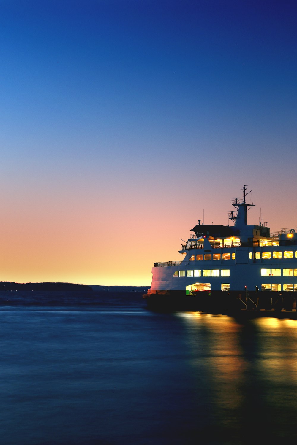 beleuchtetes Kreuzfahrtschiff auf See, aufgenommen während der goldenen Stunde