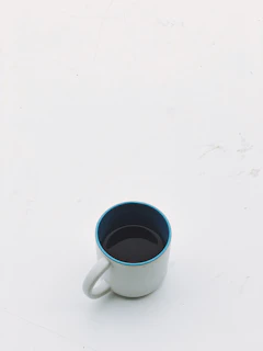 A sleek golden mug with custom designs placed on a minimalist white and black desk setup.