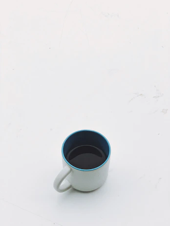 A sleek golden mug with custom designs placed on a minimalist white and black desk setup.